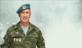 a man in a military uniform with a blue beret is standing in the snow .