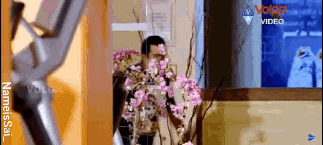 a man with flowers on his face stands in front of a screen that says volco video