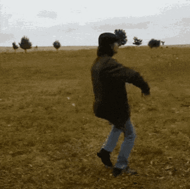 a person in a black jacket is dancing in a field