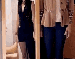 a man and a woman are standing next to each other in a doorway . the woman is wearing a black dress .