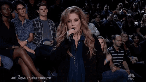 a woman singing into a microphone in front of a crowd with the hashtag #elvisallstartribute