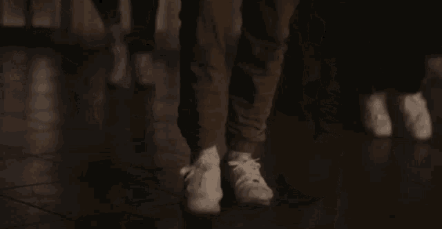 a close up of a person 's feet wearing white sneakers dancing on a wooden floor .