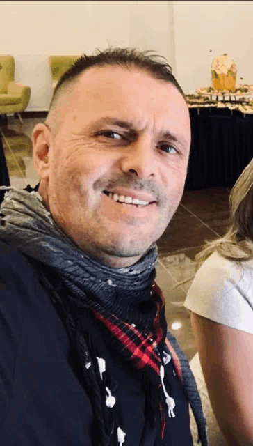 a man with a scarf around his neck is smiling