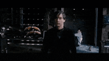 a man in a white shirt is standing in front of a fire explosion .