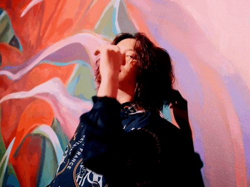 a woman covering her face in front of a wall with a painting that says france