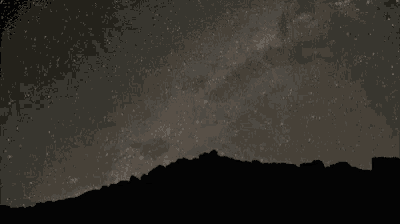 the milky way galaxy is visible in the night sky over a mountain range .