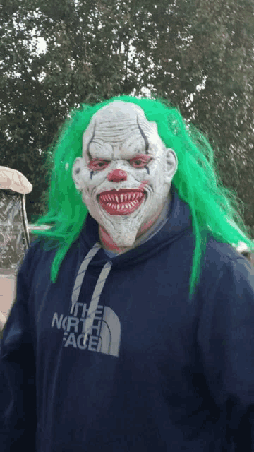 a man in a clown mask is wearing a north face sweatshirt