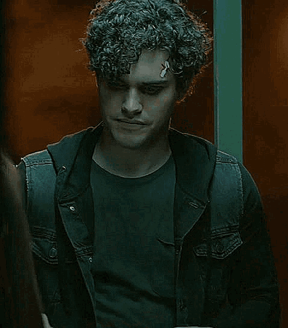a man with curly hair is standing next to a woman and reading a newspaper .