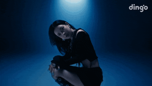 a woman is squatting down in front of a blue background with the word dingo on it