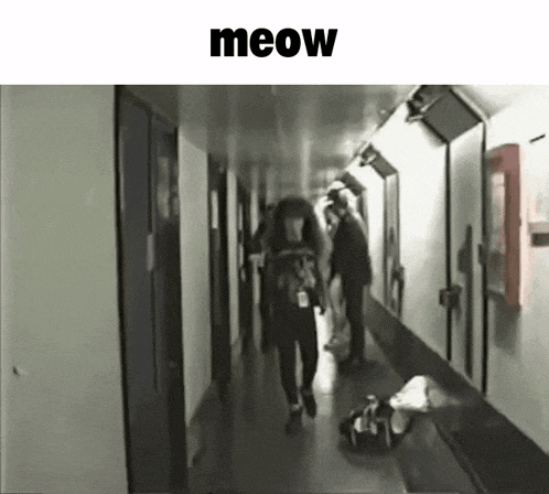 a woman with long hair is walking down a hallway with the word meow above her .