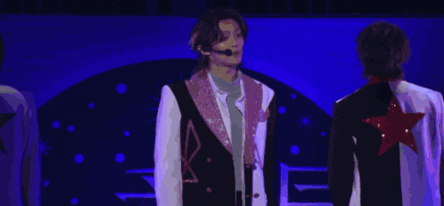 a man with a microphone on his head is singing into a microphone .