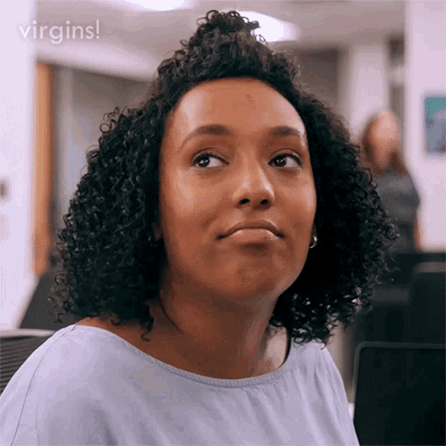 a woman with curly hair is making a funny face and the words virgins are behind her .