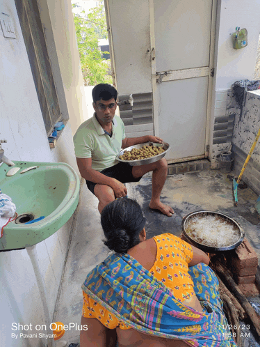 a man sitting next to a woman holding a tray of food and a shot on oneplus