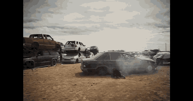 a bunch of cars are stacked on top of each other in the dirt