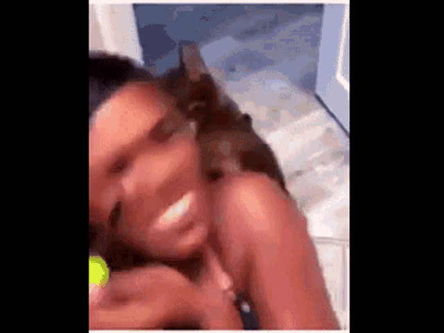 a woman is holding a tennis ball and playing with a cat .