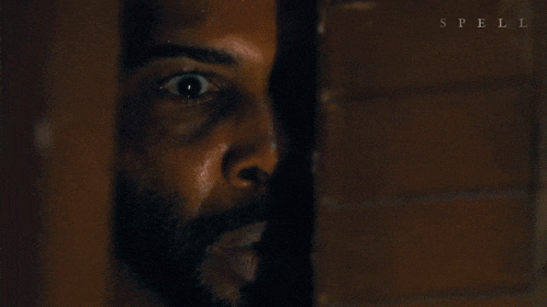 a close up of a man 's face behind a wooden wall with spell written on it