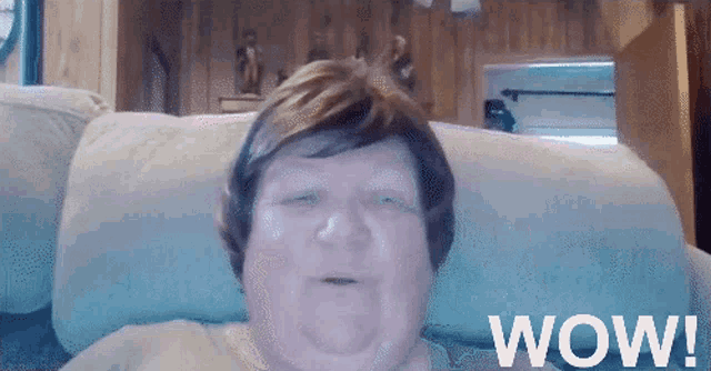 an elderly woman sitting on a couch with the word wow on the bottom right
