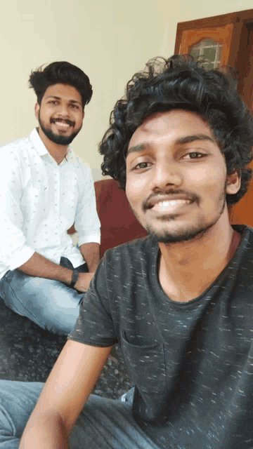 two young men are posing for a picture and one is wearing a black t-shirt