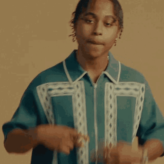 a young man in a green shirt is dancing with his hands