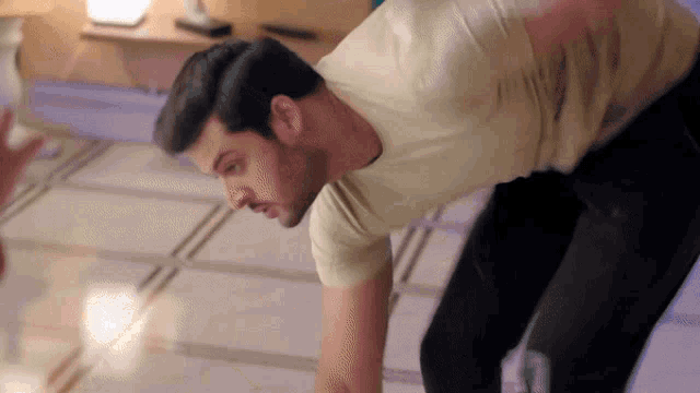 a man in a yellow t-shirt is bending over