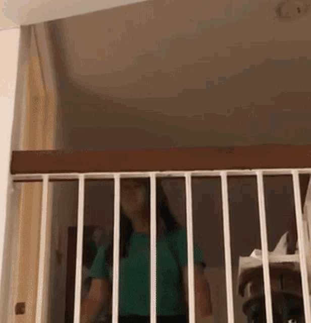 a woman in a green shirt is standing in front of a railing