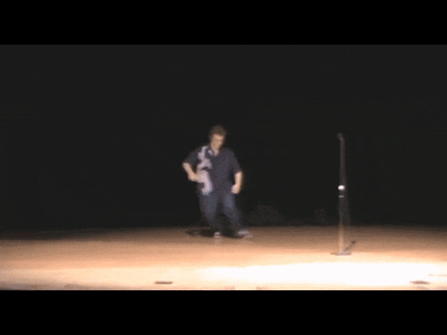 a person doing a handstand on a stage with a microphone in the background