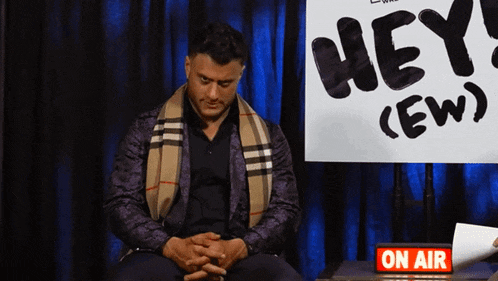a man sits in front of a sign that says hey ( ew )
