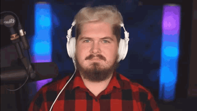 a man wearing headphones and a red and black plaid shirt stands in front of a microphone that says mike