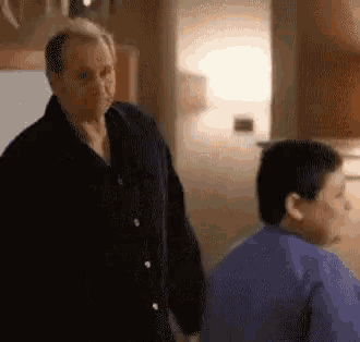a man and a boy are standing next to each other in a living room .