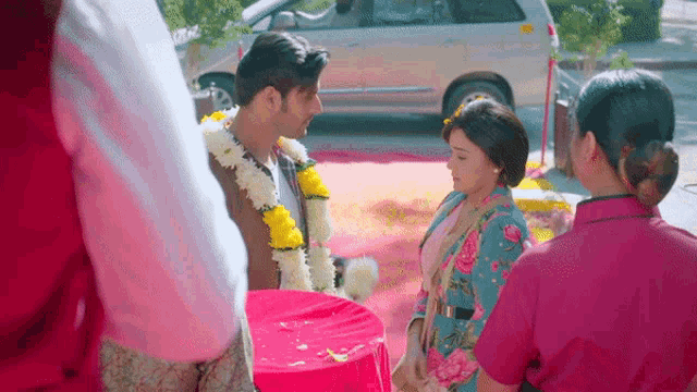 a man wearing a garland of flowers is standing next to a woman