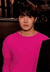 a young man wearing a pink sweater and a black jacket