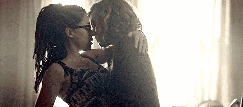 a man and a woman are kissing in front of a window in a room .