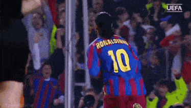 a soccer player wearing a number 10 jersey stands in front of a crowd .