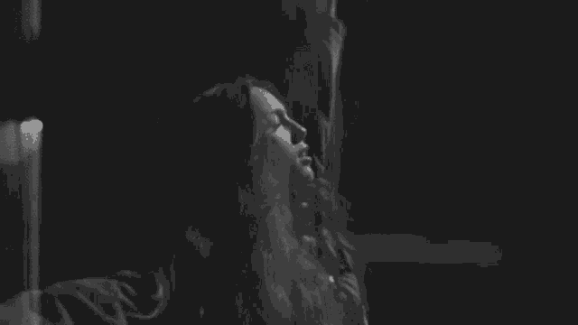 a black and white photo of a woman taking a picture of herself in a dark room .