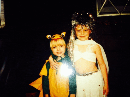 a girl in a dragon costume and a girl in a white dress pose for a photo