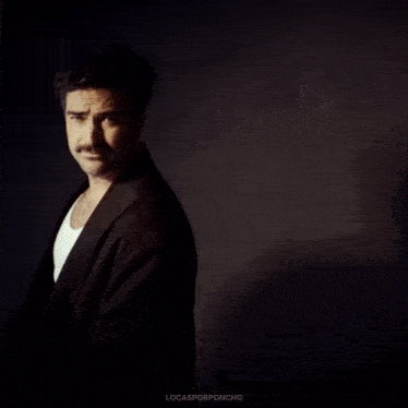 a man with a mustache is wearing a white tank top and a black jacket