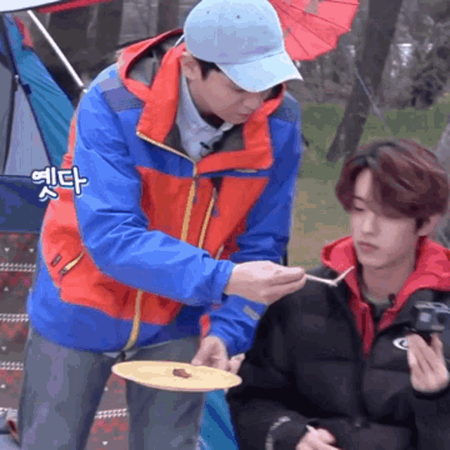 a man in a blue hat holds a plate with food on it