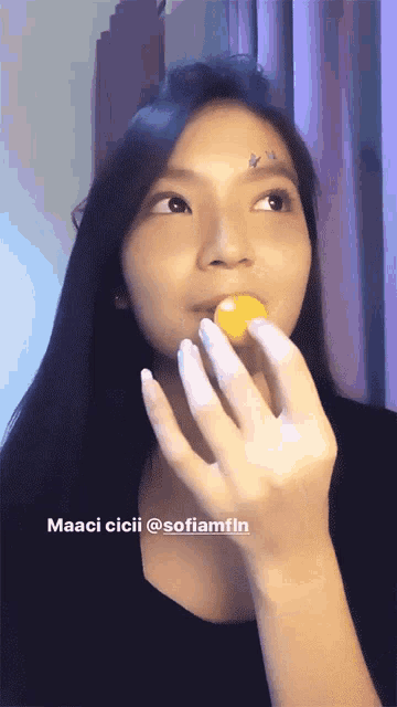 a woman is holding a yellow ball in her mouth with a caption that says maaci cici @sofiamfin