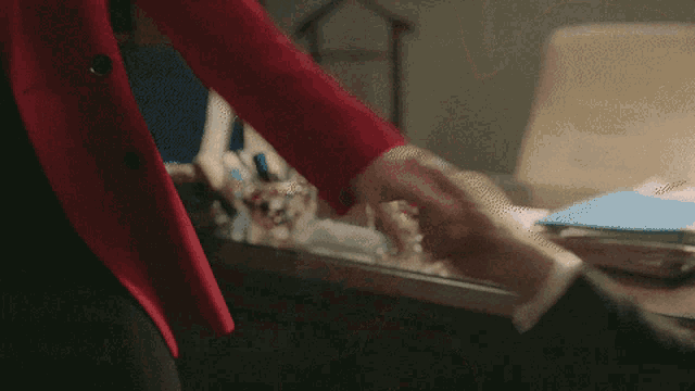 a person wearing a red jacket is standing in front of a desk