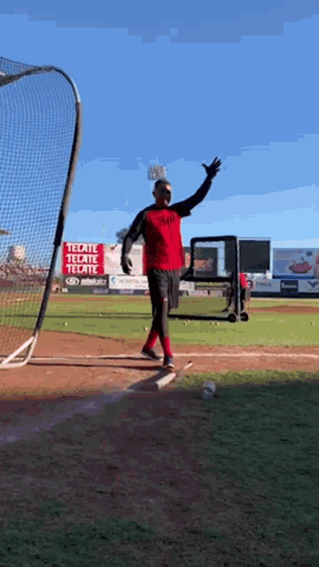 a man stands on a baseball field in front of a tecate tecate sign