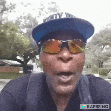 a man wearing a hat and sunglasses is making a funny face