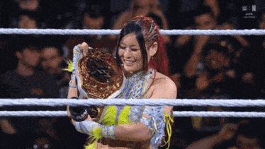 a woman in a wrestling ring is holding a championship belt and smiling