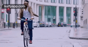 a man is riding a bicycle down a city street in front of a building .