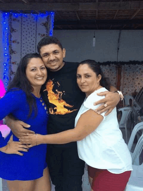 a man wearing a shirt with flames on it is surrounded by two women