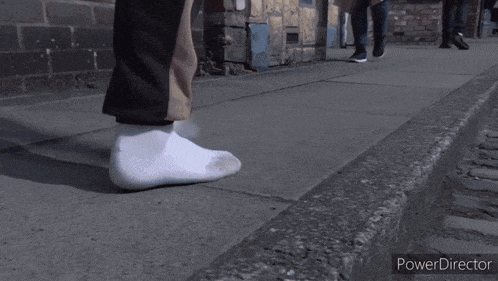 a group of people are walking down a cobblestone street and the power director is displayed