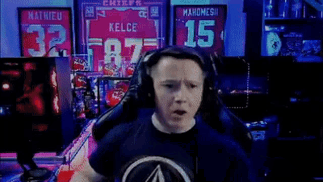 a man wearing headphones is sitting in front of a display of jerseys including one for kelce