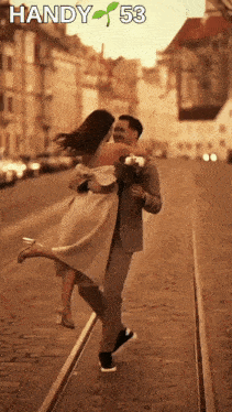 a man is holding a woman in his arms with handy 53 on the bottom right