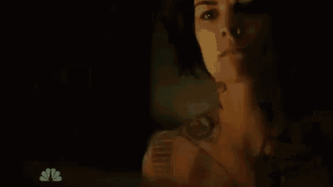 a man is drinking a glass of water in a dark room .