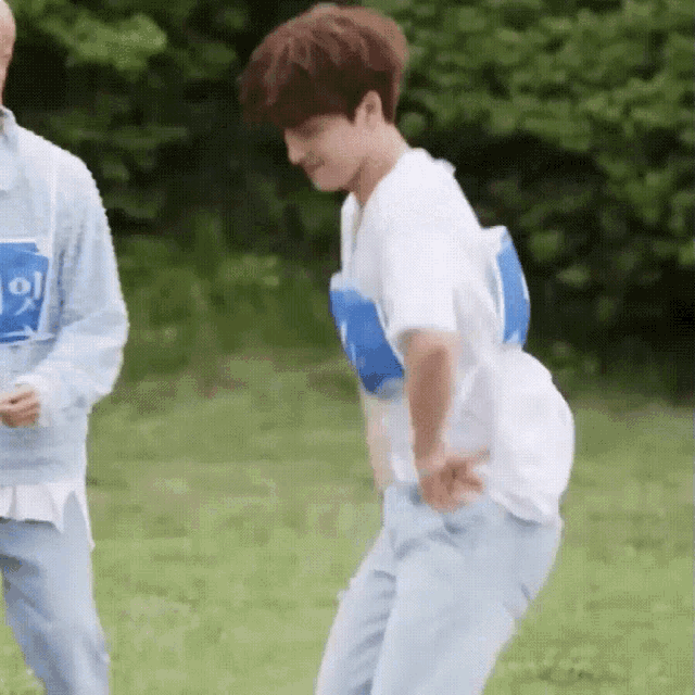a man in a white shirt and blue pants is dancing in a field .