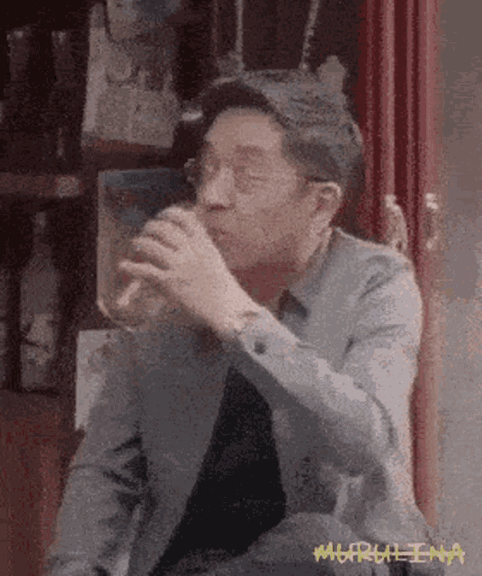 a man drinking from a glass with the word marulina written on the bottom right